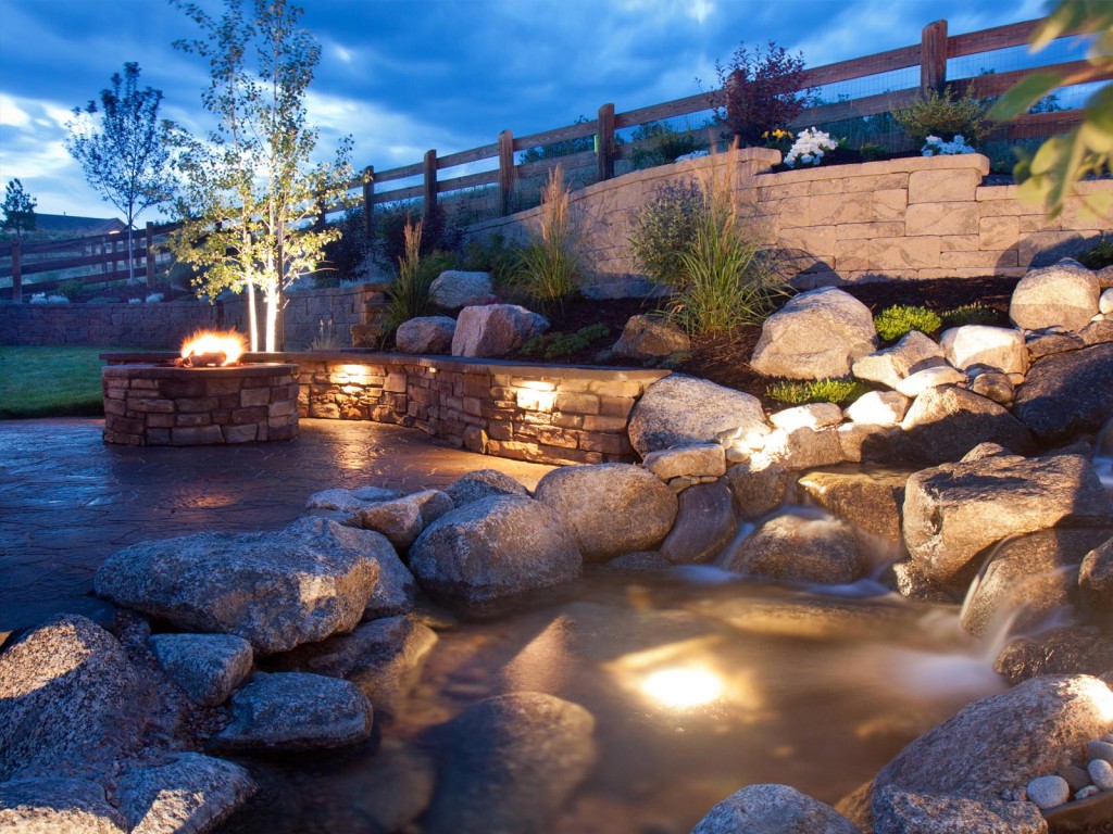a stone wall with lights and a firepit